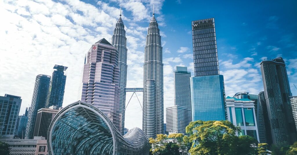 Cityscape with famous Petronas Twin Towers amidst glass contemporary skyscrapers and futuristic pedestrian overpass located in Kuala Lumpur
